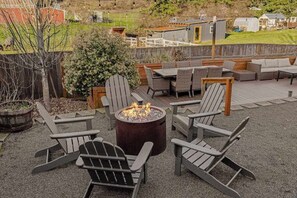 Eine Terrasse mit Adirondack-Stühlen, einer Feuerstelle und einem Deck mit Gartenmöbeln.