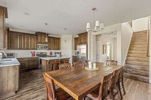 A spacious kitchen with wooden cabinets, a central island, and a dining area with a wooden table and chairs.