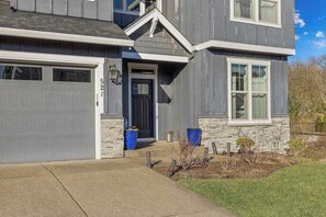 A two-story house with a garage, a front door, and a small front yard with a pathway leading to the entrance. - 5BR House - Fire Pit - Gas Grill - Washer & Dryer (Newberg)