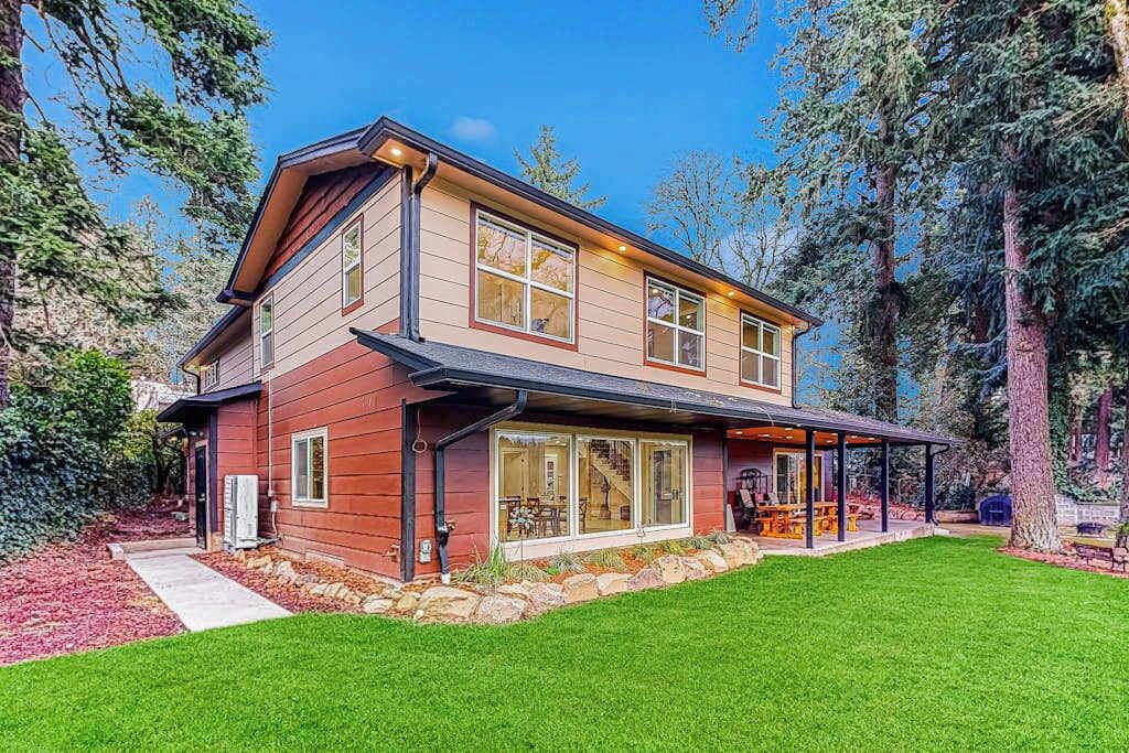 A two-story house with a covered patio and a stone foundation.