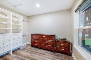 Una habitació amb un armari de fusta, un aparador blanc i una prestatgeria.