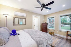 A bedroom with a bed, a ceiling fan, a dresser, a window with a view, and a lamp. - 3BR river-view with deck, grill, & firepit (Milwaukie)