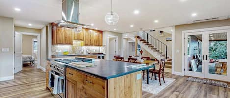 Une cuisine moderne avec des meubles en bois, un îlot central et un escalier menant à un autre niveau.