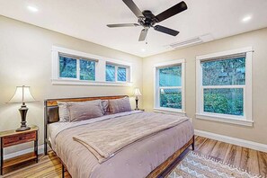 A bedroom with a bed, two bedside tables, a ceiling fan, and three windows. - 3BR river-view with deck, grill, & firepit (Milwaukie)