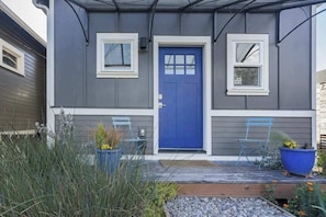 A residential building with a blue front door, two windows, and a porch with chairs and planters. - Blue Door Micro-Loft in Hip and Arty Location (Portland)