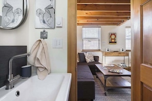 A modern bathroom with a sink, towel, and artwork on the wall. - Blue Door Micro-Loft in Hip and Arty Location (Portland)