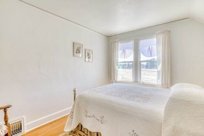 Ein Schlafzimmer mit einem Bett, einem Fenster mit Vorhängen und einer Heizung.