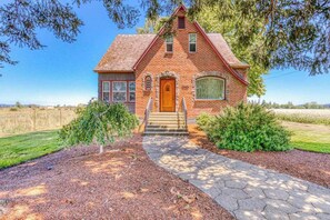 A brick house with a front porch, a wooden door, and a small set of stairs leading to the entrance. - Historic 4BR Valleyview Oregon Wine Country DogsOK (McMinnville)
