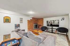 A living room with a brick fireplace, a billiards table, and a television.