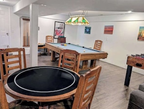 A room with a pool table, chairs, a dining table, and a foosball table. - Dog-friendly 5BR with game room & 2 fireplaces (Portland)