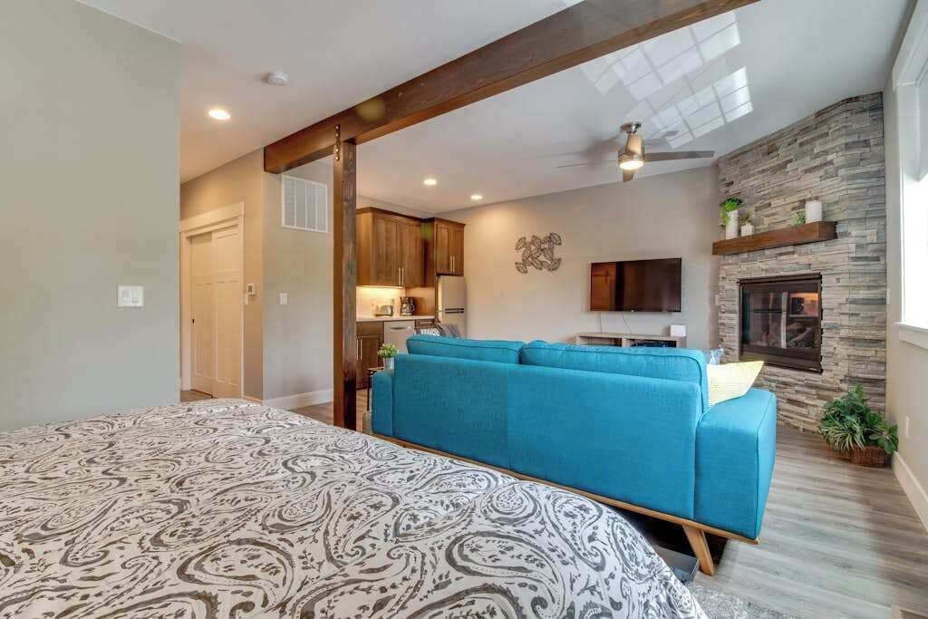 Ein Schlafzimmer mit einem gemusterten Bett, einem blauen Sofa, einem Kamin und einer Küche im Hintergrund.