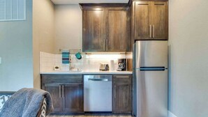 A compact kitchen with wooden cabinets, a stainless steel refrigerator, and a dishwasher. - High-End Studio Oregon Wine Country (McMinnville)