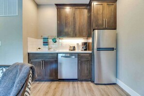 A compact kitchen with wooden cabinets, a stainless steel refrigerator, and a dishwasher. - High-End Studio Oregon Wine Country (McMinnville)