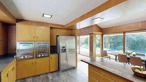 A modern kitchen with built-in appliances, a dining area with natural light, and a view of the outdoors. - 3BR home with pool, patio, fireplace, WIFI (Portland)