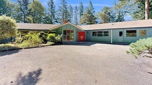 A two-story building with a red door, surrounded by trees and a clear sky. - 3BR home with pool, patio, fireplace, WIFI (Portland)