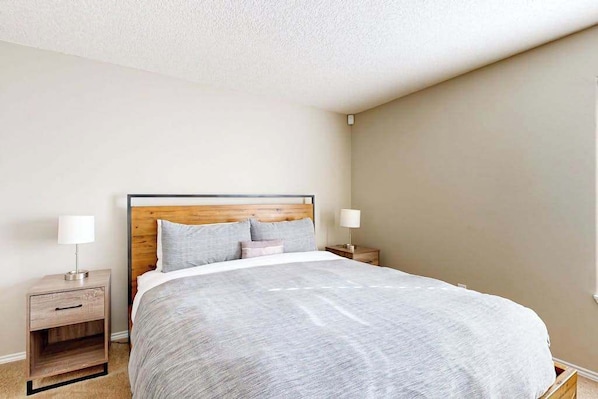 A bedroom with a bed, two bedside tables, and a nightstand. - 3BR Oregon Wine Country - Fireplace - Patio (McMinnville)