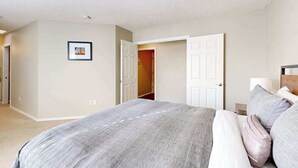 Een slaapkamer met een bed, een deur en een aan de muur bevestigd schilderij.