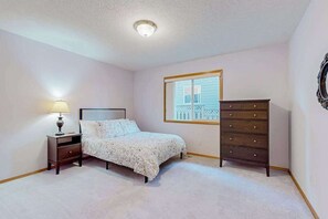 A bedroom with a bed, a nightstand with a lamp, a dresser, and a window with a view. - Custom-built 2BR with deck & massage chairs (Gresham)