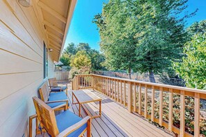 A wooden deck with outdoor seating and a view of trees and a fence. - Custom-built 2BR with deck & massage chairs (Gresham)