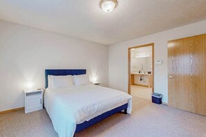 A bedroom with a bed, bedside tables, a wardrobe, and a bathroom visible through an open door. - Custom-built 2BR with deck & massage chairs (Gresham)