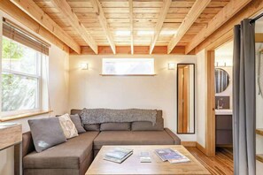 Ein gemütliches Zimmer mit Holzbalkendecke, einer Couch, einem Couchtisch mit Zeitschriften und einem Fenster.
