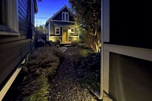 Ein Wohnhaus mit einem Weg, der zu einem Gebäude führt, umgeben von Pflanzen.