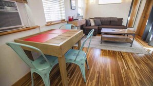 A compact living space with a wooden dining table, two chairs, a sofa, and a small coffee table. - Micro-Loft Surrounded by Gardens in Hip Location (Portland)