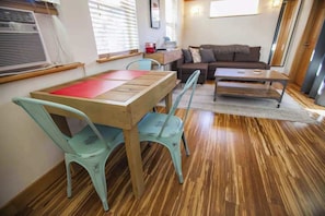 Ein gemütlicher Wohnbereich mit einem Holztisch, zwei Stühlen, einer Couch und einem kleinen Couchtisch.