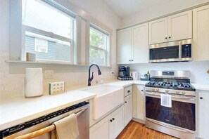 A modern kitchen with white cabinetry, a built-in microwave, a stove, and a dishwasher. - 3 BR - Downtown Newberg - Wine Tasting - WiFi (Newberg)