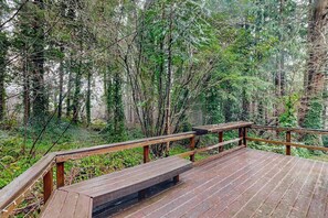 A wooden deck with railings overlooking a forested area. - 2BR cabin with loft in wooded setting with WiFi (Beaverton)