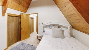 A bedroom with a sloped ceiling, a bed, a bedside table, and a wardrobe. - 2BR cabin with loft in wooded setting with WiFi (Beaverton)