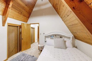 Ein Schlafzimmer mit geneigter Decke, einem Bett, einem Nachttisch und einem Kleiderschrank.