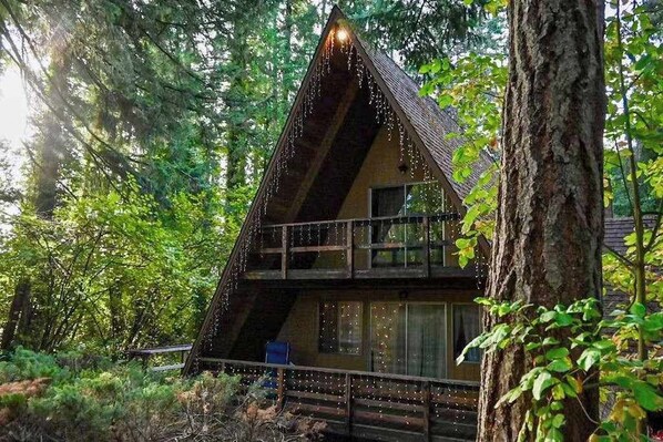 A cabin with a sloped roof, a balcony, and a deck surrounded by trees. - 2BR cabin with loft in wooded setting with WiFi (Beaverton)