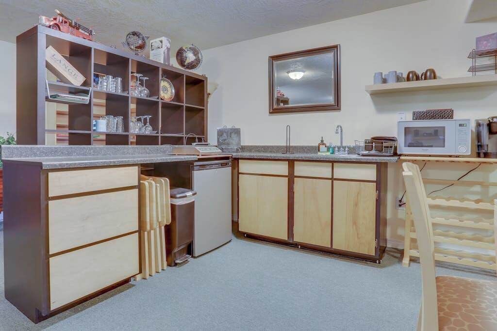 Eine kleine Küche mit Holzschränken, einer eingebauten Mikrowelle und einem kleinen Kühlschrank.