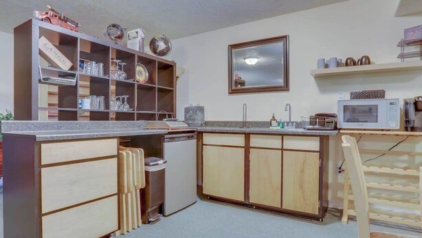 A compact kitchen with wooden cabinets, a built-in microwave, and a small refrigerator. - Cheery 2BR Golf Course View Oregon Wine Country (McMinnville)
