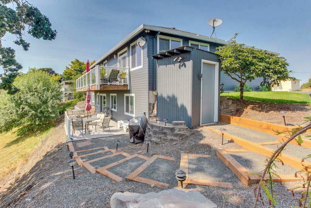 Een tweelaags huis met een overdekt terras, een schotelantenne en een kleine tuin met een trap naar een terras.