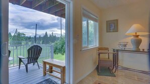 A room with a wooden deck, a chair, a table, and a lamp. - Cheery 2BR Golf Course View Oregon Wine Country (McMinnville)