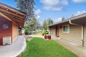 A residential property with a well-maintained lawn, a small garden area with potted plants, and a visible outdoor seating area. - Delightful 2BR Lakefront - Patio (Lake Oswego)