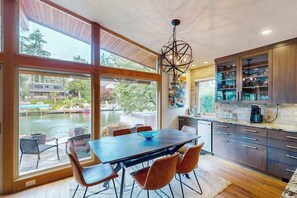 A modern kitchen with a dining area, large windows, and a view of a pool. - Delightful 2BR Lakefront - Patio (Lake Oswego)