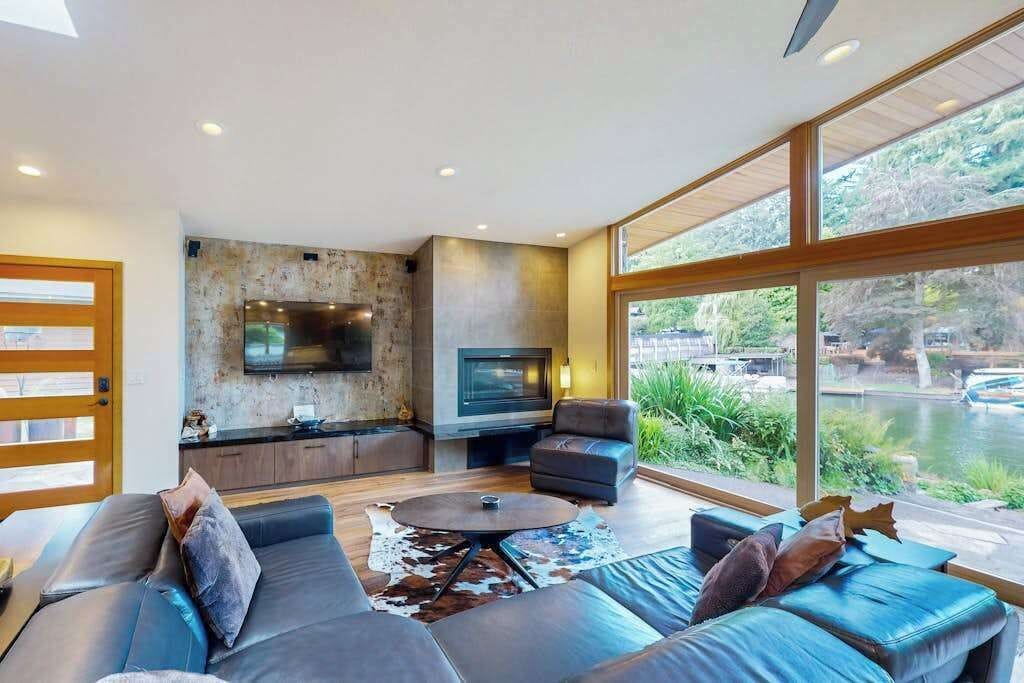 A modern living room with a fireplace, comfortable seating, and a large window overlooking a body of water.