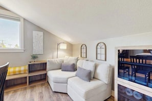 En moderne stue med en hjørnesofa, et lille bord og et vindue med udsigt.