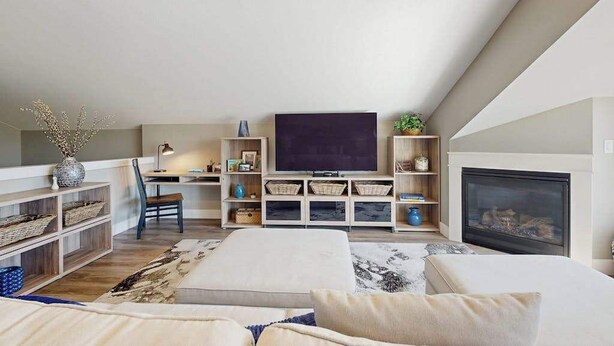 Un salon moderne de style loft, doté d’un grand téléviseur à écran plat, d’une cheminée et d’un coin salon confortable.