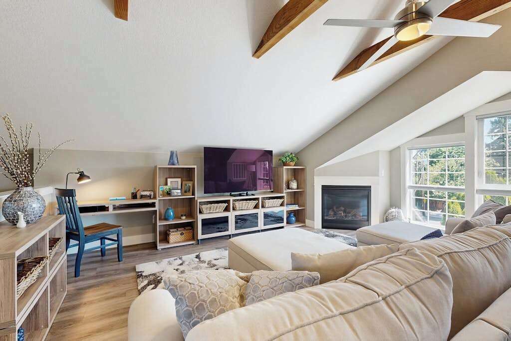 Una sala de estar moderna con chimenea, televisor y un ventanal grande.