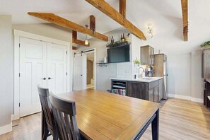 A modern kitchen with wooden beams, a dining table with chairs, and a built-in island with a sink. - High-End Rooftop Studio Oregon Wine Country (McMinnville)