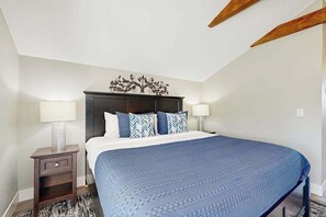 Une chambre à coucher avec un lit, des tables de chevet, des lampes et une tête de lit décorative.
