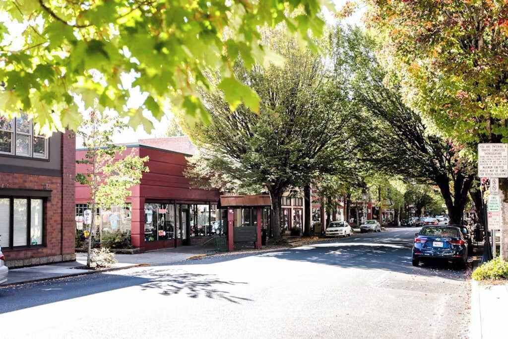 A street lined with trees and buildings, including a red brick building with a covered entrance.