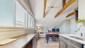Une cuisine moderne dotée d’un long comptoir, de poutres en bois et d’un coin repas avec une table et des chaises.