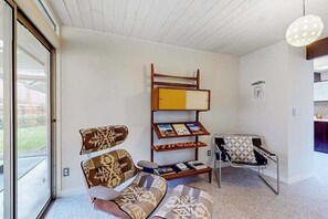 Ein modernes Wohnzimmer mit einer Couch, einem gemusterten Sessel, einem Bücherregal und einem Stuhl.