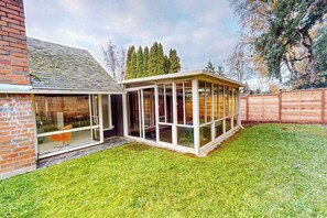 Et hus med en glasindhegnet terrasse, en murstensmur og et træhegn.