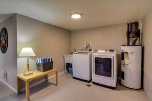 A laundry room with a washing machine, dryer, and a small table with a lamp and basket. - Wine Country 3BR Mountainview Oregon Wine Country (Dundee)